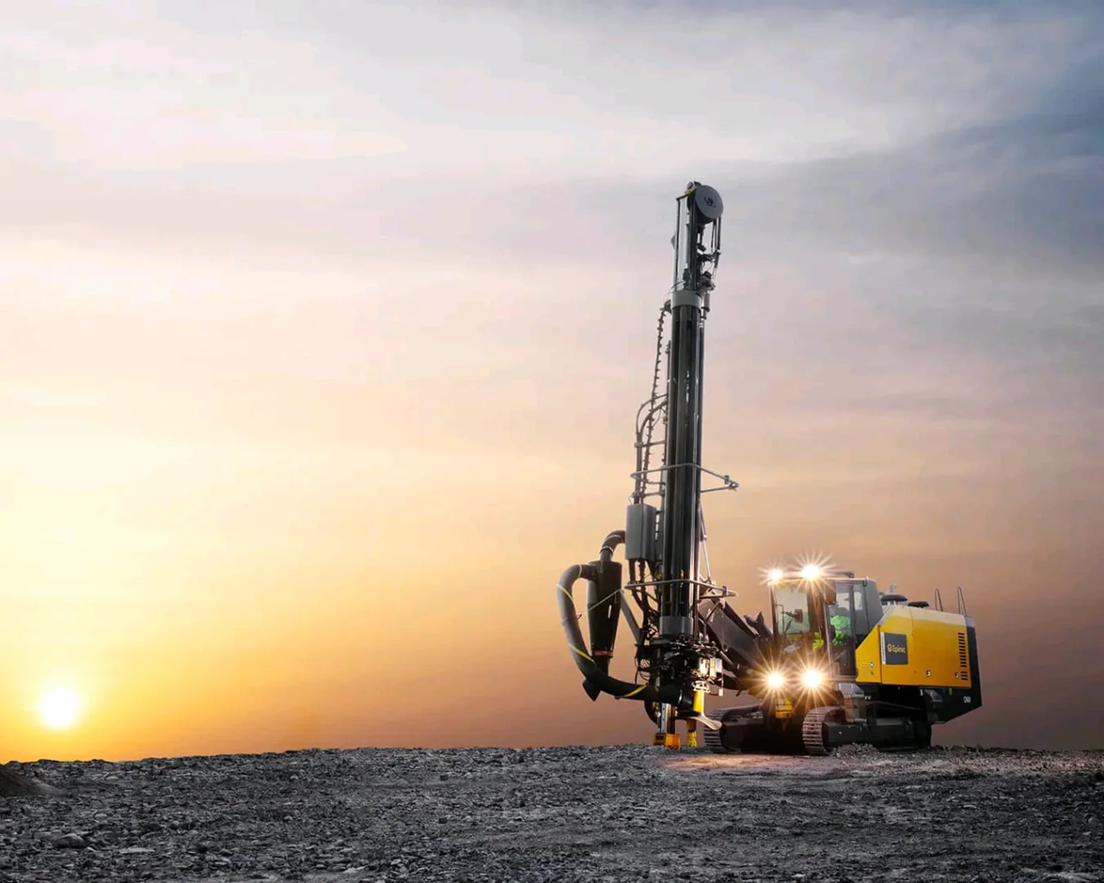 Mine drill rig operating at sunset